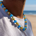 Collana uomo Taormina in vetro di Murano azzurra e gialla indossata in spiaggia - Dandy Street